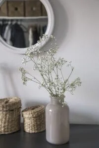 This image is of a dorm decor vase with plants and a mirror