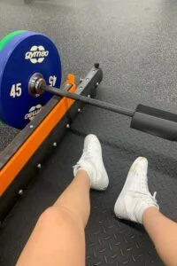 This image is of a bar at a gym with weights on it and shoes