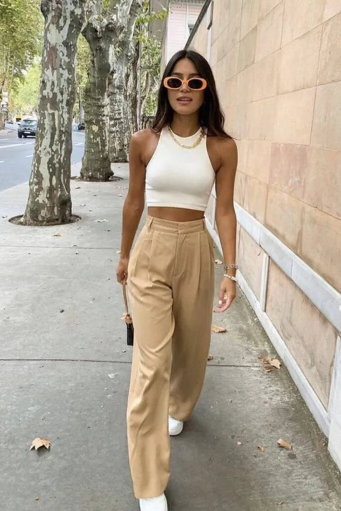 This image is of tan colored pants paired with a white crop top on a girl walking through her college