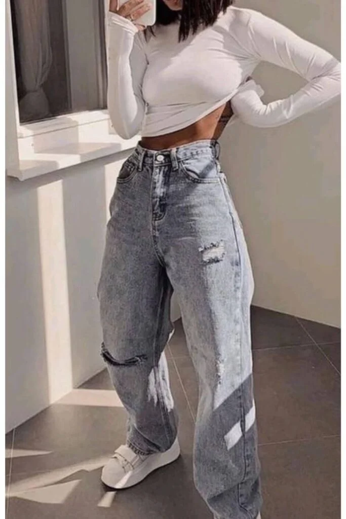 This image is of a girl wearing baggy mom jeans and a form fitting white crop top with chunky white shoes