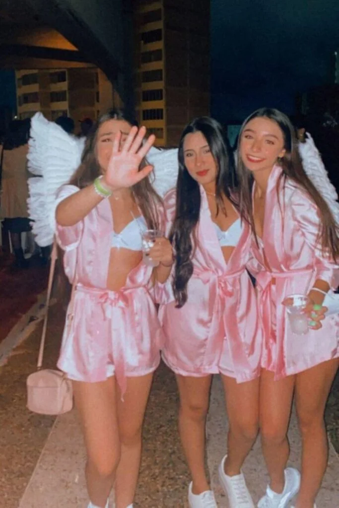 This image is of a group of college friends dressed up as angels for halloween. They are wearing pink nightgowns and white angel wings