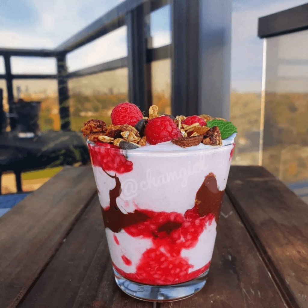 This image is of a yogurt parfait with strawberry and chocolate adn granola on top. An easy high protein breakfast option at home or to go
