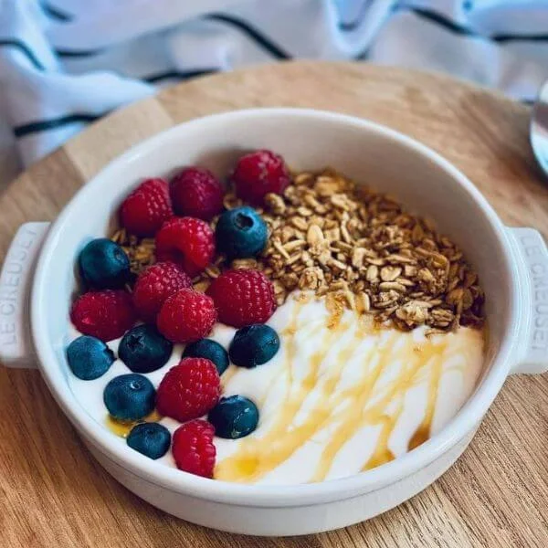 Image of yogurt bowl topped with berries, granola, and honey