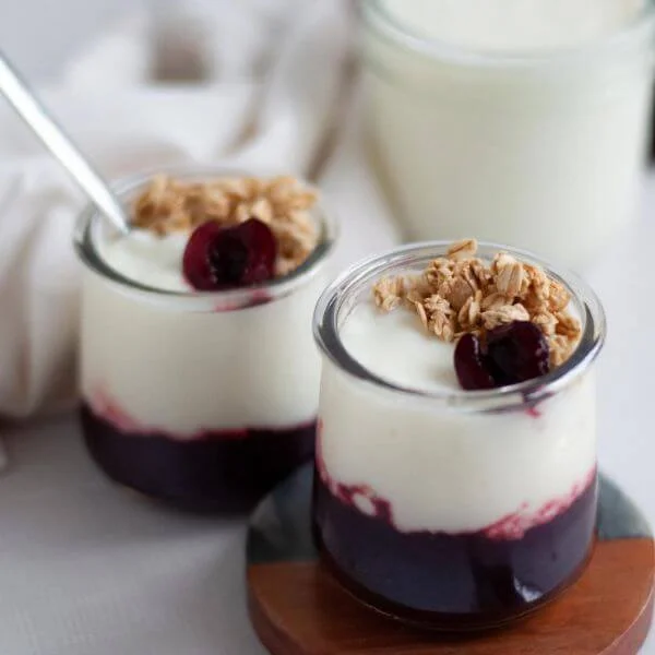 Image of yogurt with berry sauce and granola on top in small glass jars