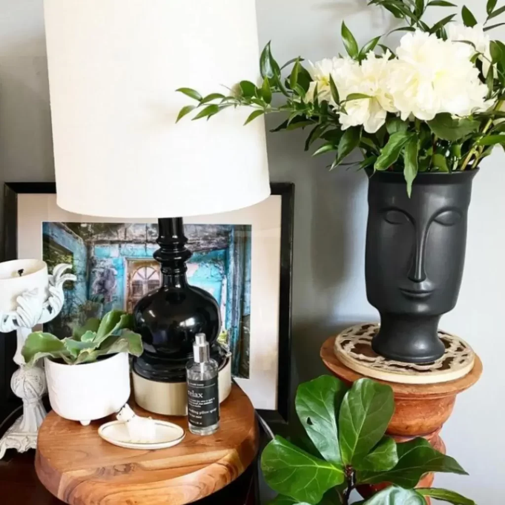 This photo is of a nightstand with multiple plants and a perfume