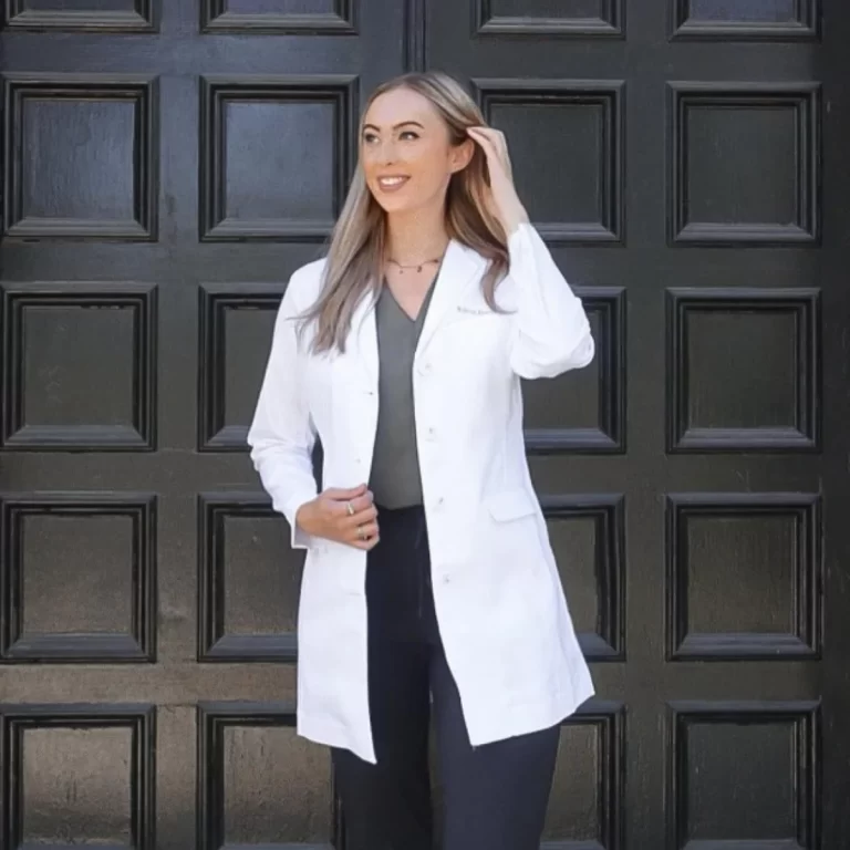 Photo of a women smiling in a white lab coat button up